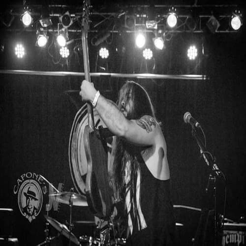 Joey Shaw singing into the mic mid-set, guitar raised overhead